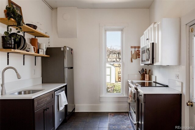 kitchen with dark brown cabinets, open shelves, appliances with stainless steel finishes, a sink, and a healthy amount of sunlight
