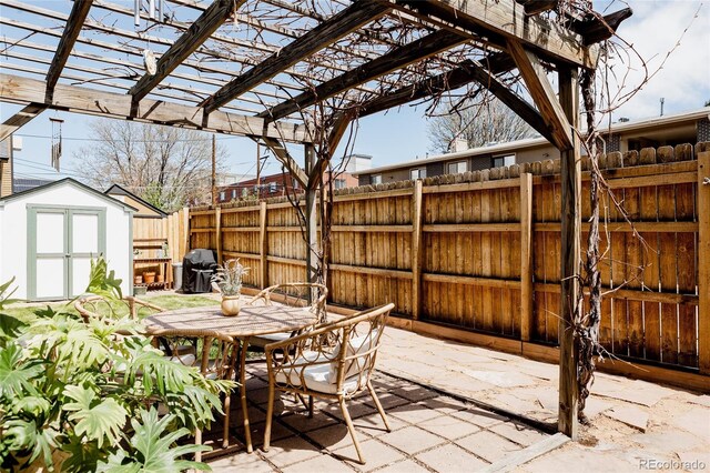 view of patio / terrace with fence, outdoor dining space, a pergola, a storage shed, and an outdoor structure