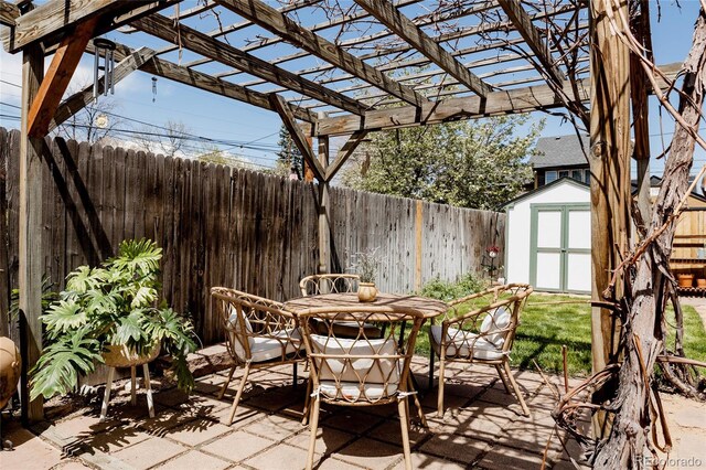 view of patio featuring outdoor dining area, a storage shed, an outdoor structure, a fenced backyard, and a pergola
