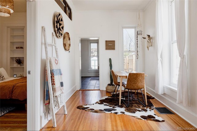 dining room with crown molding, baseboards, wood finished floors, and visible vents