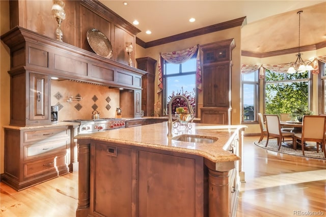 17540 Pond View Pl, Colorado Springs, CO 80908 - kitchen with a sink, light wood finished floors, ornamental molding, light stone counters, and a kitchen island with sink