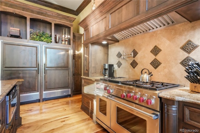 17540 Pond View Pl, Colorado Springs, CO 80908 - kitchen featuring double oven range, custom exhaust hood, light wood finished floors, light stone counters, and ornamental molding