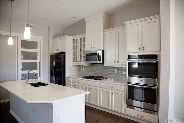 kitchen featuring black appliances, sink, an island with sink, pendant lighting, and white cabinets