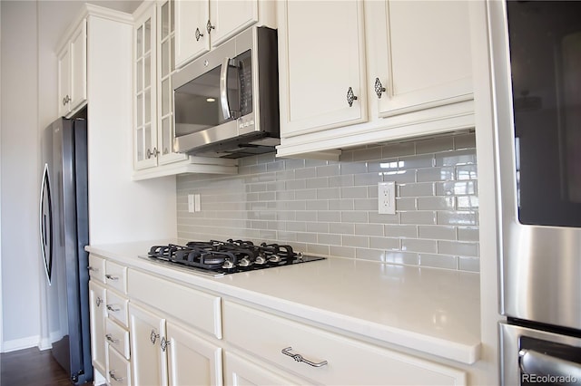 kitchen featuring white cabinetry, stainless steel appliances, decorative backsplash, and dark hardwood / wood-style flooring