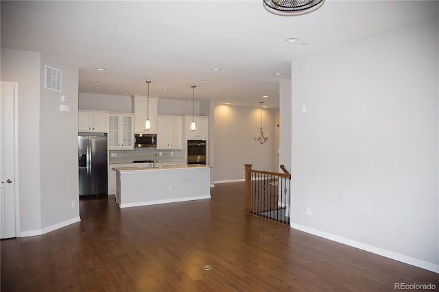 kitchen featuring dark hardwood / wood-style floors, hanging light fixtures, stainless steel appliances, and a center island with sink