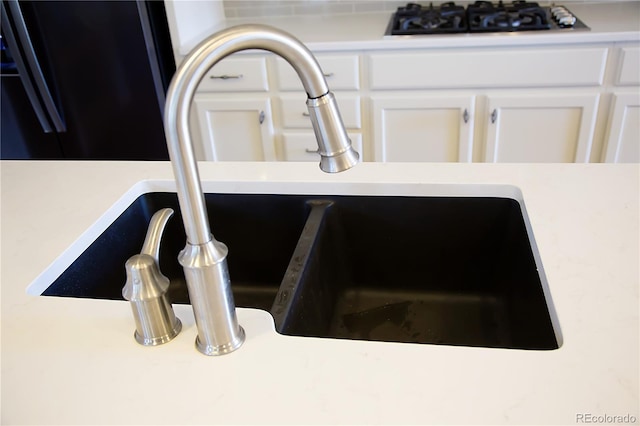 details featuring black gas stovetop, white cabinetry, and sink