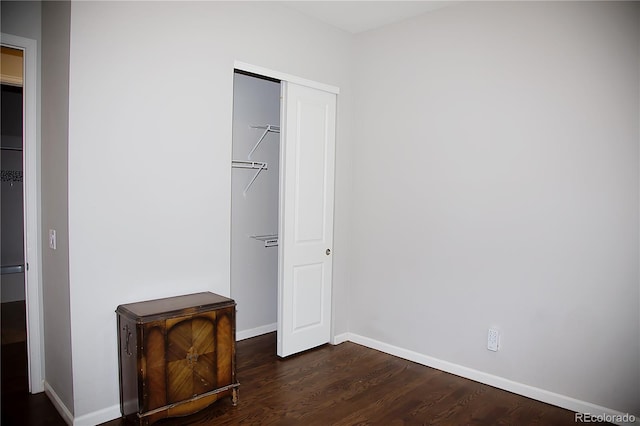 unfurnished bedroom featuring a spacious closet, a closet, and dark hardwood / wood-style flooring