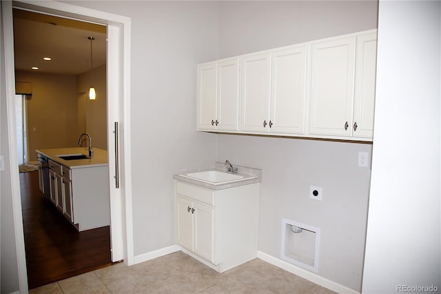 laundry area featuring light tile patterned floors, electric dryer hookup, cabinets, and sink