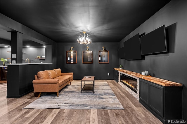 living area featuring a glass covered fireplace, wood finished floors, and a chandelier