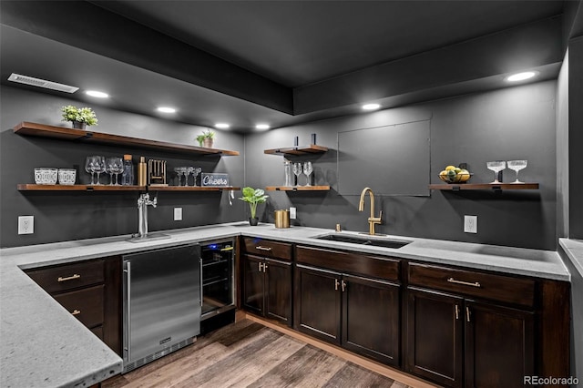 bar with refrigerator, indoor wet bar, wood finished floors, and a sink