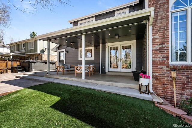 back of property featuring brick siding, fence, and french doors