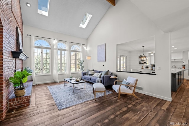 living area featuring dark wood finished floors, a healthy amount of sunlight, a skylight, and high vaulted ceiling
