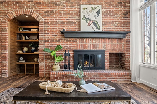 living area featuring wood-type flooring, a fireplace, and baseboards