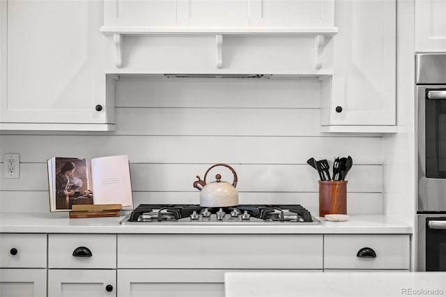 kitchen featuring custom exhaust hood, appliances with stainless steel finishes, white cabinetry, and light countertops