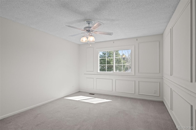 unfurnished room featuring baseboards, a ceiling fan, a textured ceiling, and carpet
