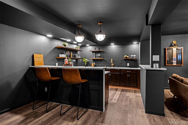 bar featuring indoor wet bar, wood finished floors, a sink, and pendant lighting