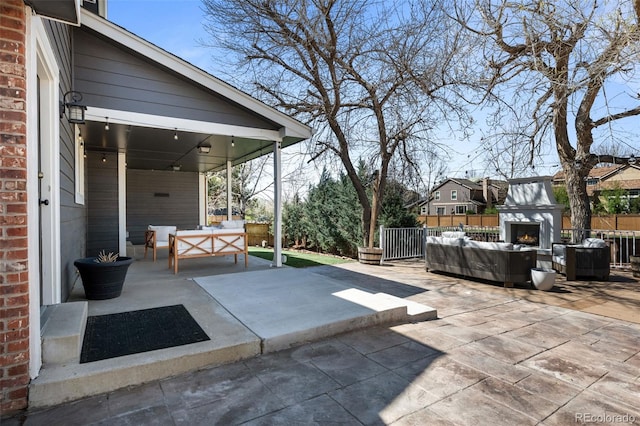 view of patio / terrace with fence and an outdoor living space with a fireplace