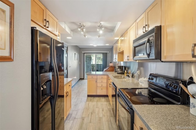 kitchen with light hardwood / wood-style floors, light brown cabinets, a tray ceiling, black appliances, and sink