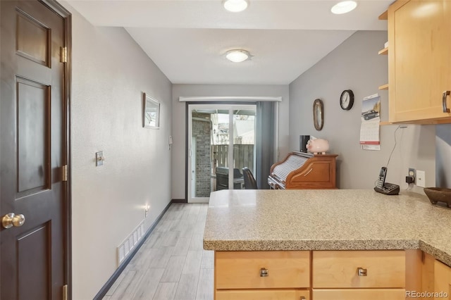 kitchen with light brown cabinetry, light hardwood / wood-style floors, and kitchen peninsula