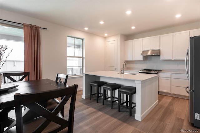 2967 S Quaker St, Morrison, CO 80465 - kitchen with appliances with stainless steel finishes, under cabinet range hood, light wood-type flooring, white cabinetry, and healthy amount of natural light