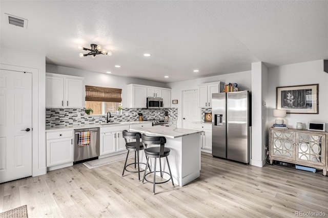 kitchen with a center island, sink, light wood-type flooring, white cabinetry, and stainless steel appliances