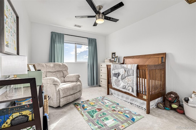 bedroom featuring light carpet, a crib, and ceiling fan