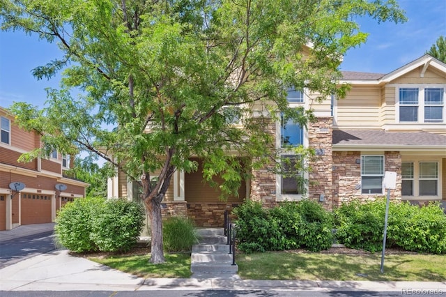14197 W 84th Cir Unit C, Arvada, CO 80005 - view of front of property featuring stone siding, a shingled roof, and an attached garage