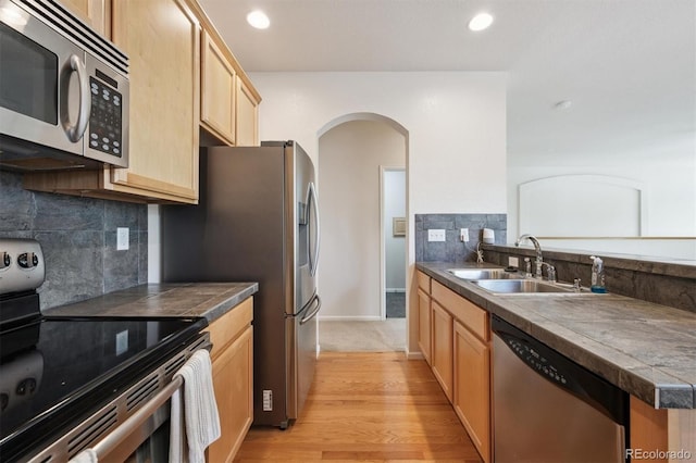 14197 W 84th Cir Unit C, Arvada, CO 80005 - kitchen with appliances with stainless steel finishes, light brown cabinets, arched walkways, light wood-style floors, and decorative backsplash