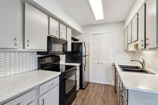1820 Newland Ct Unit 210, Lakewood, CO 80214 - kitchen featuring black appliances, a sink, light wood-type flooring, and tasteful backsplash