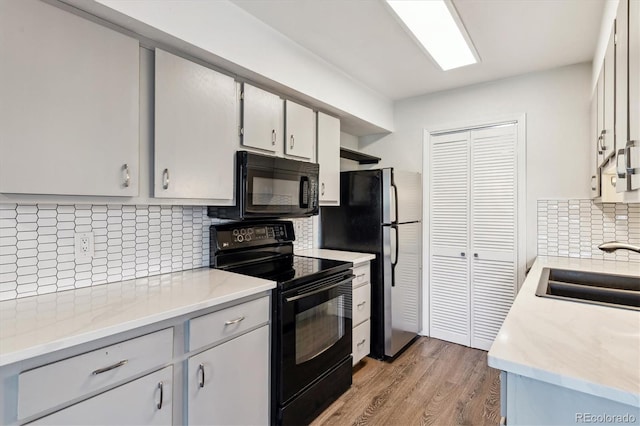 1820 Newland Ct Unit 210, Lakewood, CO 80214 - kitchen featuring black appliances, a sink, tasteful backsplash, light wood-type flooring, and light countertops