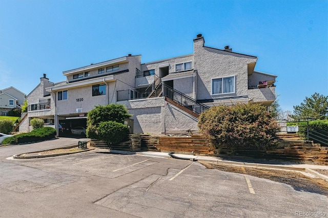 1820 Newland Ct Unit 210, Lakewood, CO 80214 - back of property with stairway, stucco siding, and uncovered parking