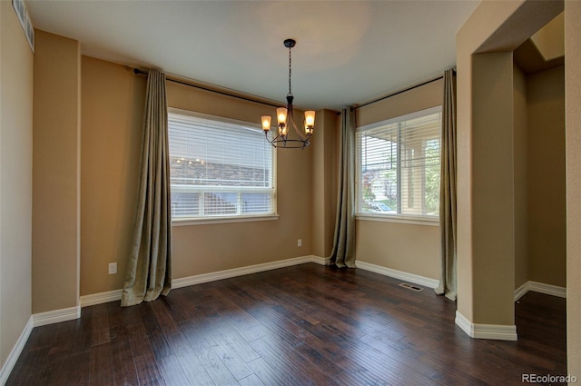 unfurnished dining area featuring an inviting chandelier, baseboards, hardwood / wood-style floors, and visible vents