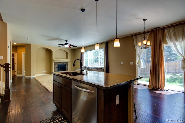 kitchen featuring stainless steel dishwasher, a sink, dark wood-style flooring, and ceiling fan with notable chandelier