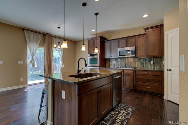 kitchen featuring appliances with stainless steel finishes, a sink, a kitchen breakfast bar, dark wood-type flooring, and backsplash