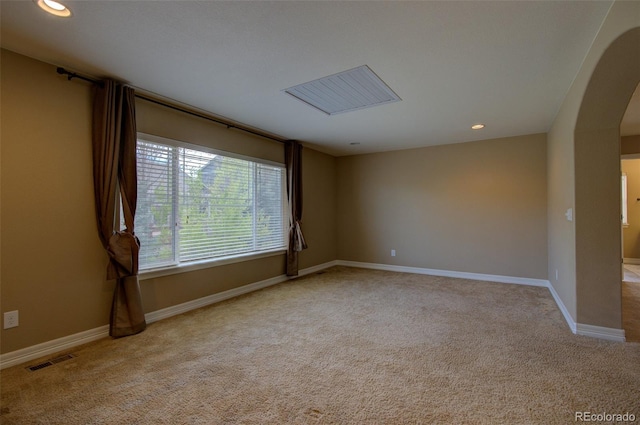 unfurnished room with arched walkways, baseboards, carpet floors, and visible vents