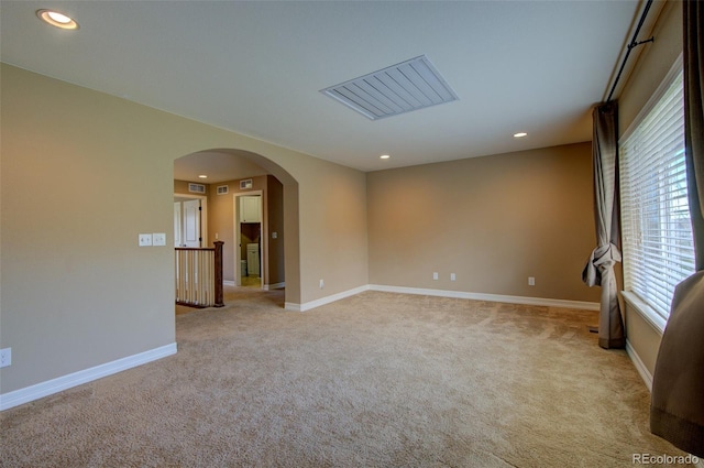 unfurnished room featuring light colored carpet, arched walkways, baseboards, and recessed lighting