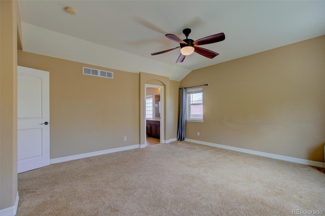 empty room with ceiling fan, light colored carpet, visible vents, baseboards, and lofted ceiling