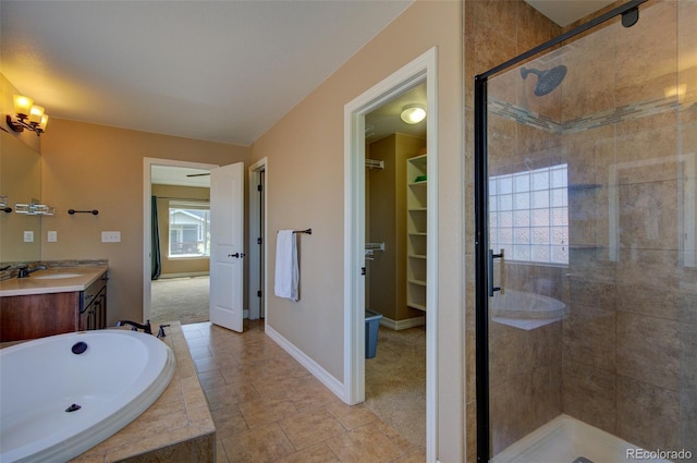 bathroom featuring vanity, a garden tub, baseboards, a walk in closet, and a shower stall