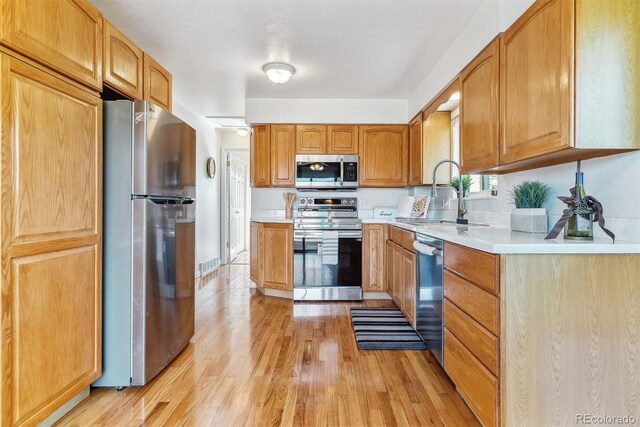 7158 W Roxbury Ave, Littleton, CO 80128 - kitchen with light countertops, light wood finished floors, appliances with stainless steel finishes, and a sink
