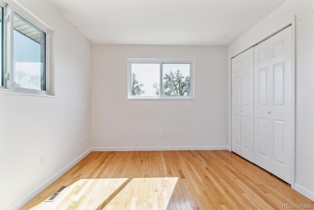 7158 W Roxbury Ave, Littleton, CO 80128 - unfurnished bedroom featuring wood-type flooring, a closet, visible vents, and baseboards