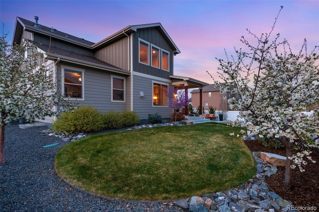 6093 Carmon Dr, Windsor, CO 80550 - back of house at dusk featuring board and batten siding and a lawn