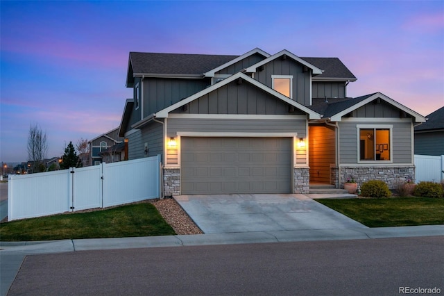 6093 Carmon Dr, Windsor, CO 80550 - craftsman house featuring a gate, fence, a front lawn, concrete driveway, and stone siding