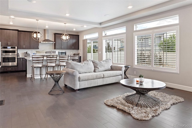 4504 N Picadilly Ct, Aurora, CO 80019 - living area with plenty of natural light, dark wood-style flooring, a chandelier, a tray ceiling, and recessed lighting