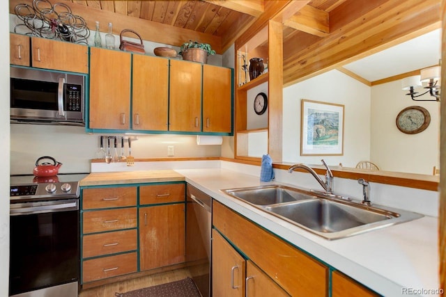 kitchen featuring brown cabinets, appliances with stainless steel finishes, light countertops, and a sink