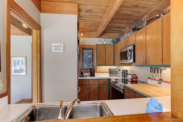 kitchen with electric stove, stainless steel microwave, light countertops, and brown cabinetry