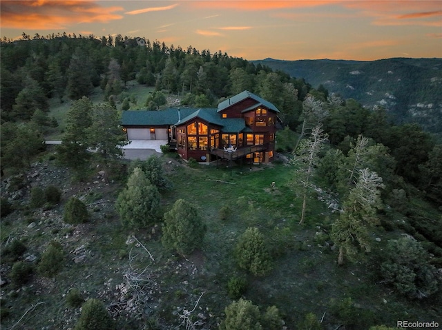 13954 Pine Country Ln, Conifer, CO 80433 - back of house at dusk with a garage, a forest view, and a wooden deck