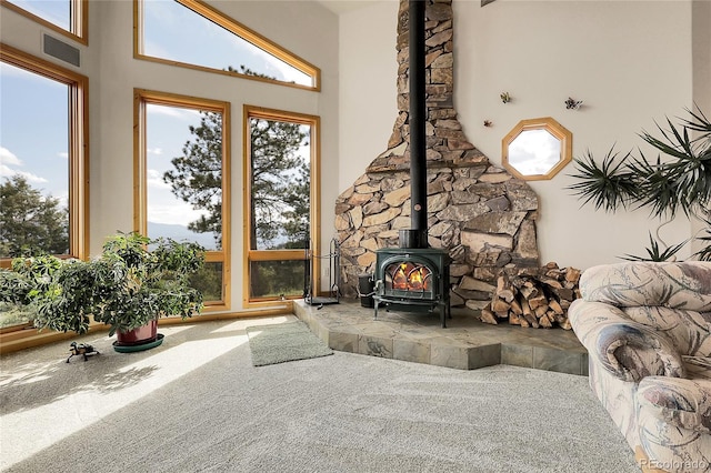 13954 Pine Country Ln, Conifer, CO 80433 - living room with a wood stove, carpet floors, a towering ceiling, and healthy amount of natural light