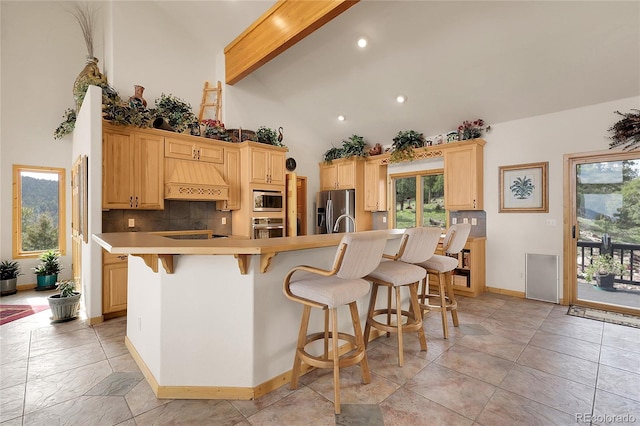13954 Pine Country Ln, Conifer, CO 80433 - kitchen featuring stainless steel appliances, high vaulted ceiling, decorative backsplash, a breakfast bar area, and custom range hood