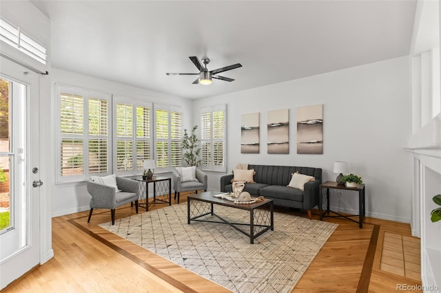 living room with ceiling fan, baseboards, and wood finished floors