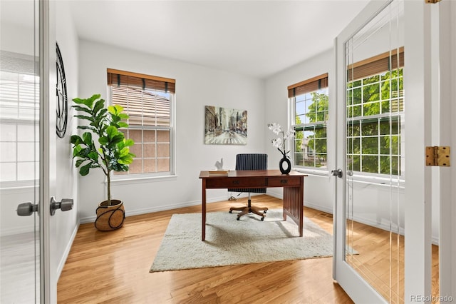 office space with french doors, light wood-style floors, and baseboards